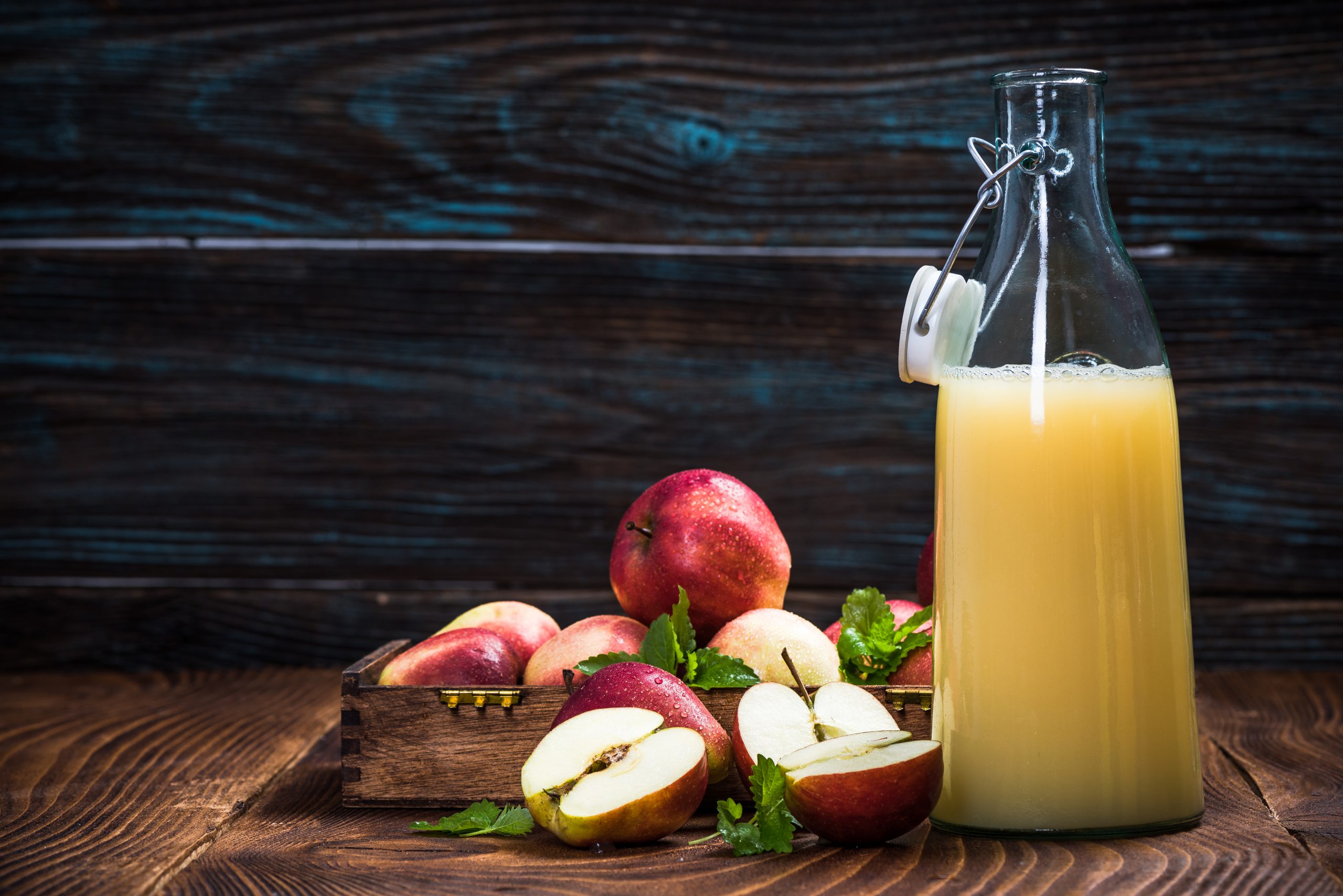 Glass of fresh organic apple juice with red and green apples in